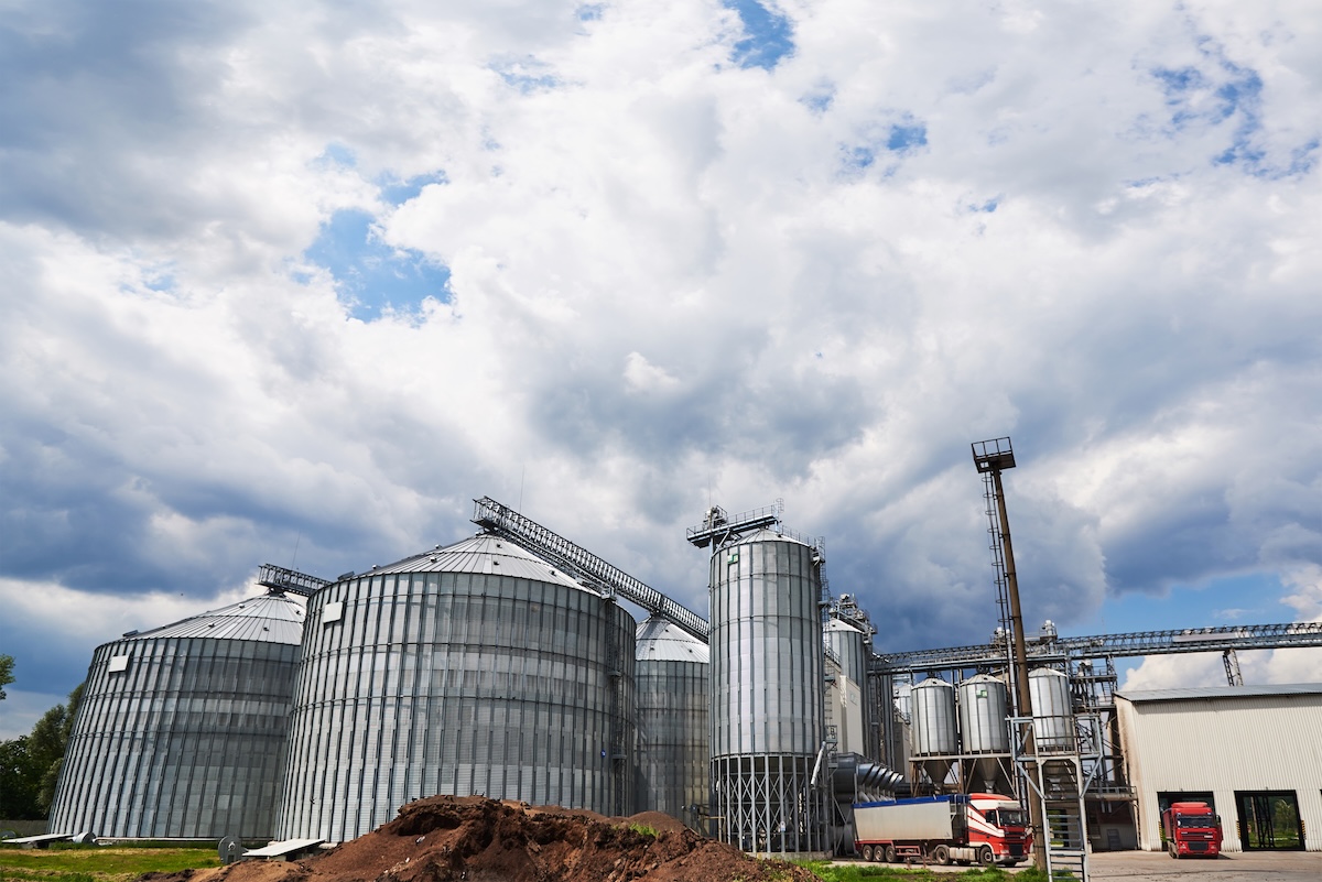 Agricultural Silos. Building Exterior. Storage and drying of grains, wheat, corn, soy, sunflower against the blue sky with white clouds.